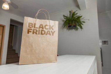 Karton poşet, arka planda özel yazı ve mutfak olan masa kahverengi kağıt ambalajına Kara Cuma yazılıydı. Kara Cuma konsepti. Ürün konsepti. Paketleme konsepti. Boşluğu kopyala