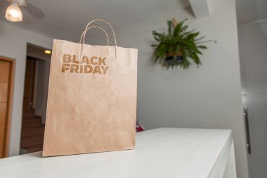 Karton poşet, arka planda özel yazı ve mutfak olan masa kahverengi kağıt ambalajına Kara Cuma yazılıydı. Kara Cuma konsepti. Ürün konsepti. Paketleme konsepti. Boşluğu kopyala