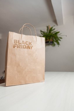 Karton poşet, arka planda özel yazı ve mutfak olan masa kahverengi kağıt ambalajına Kara Cuma yazılıydı. Kara Cuma konsepti. Ürün konsepti. Paketleme konsepti. Boşluğu kopyala