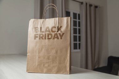 Karton poşet, arka planda özel yazı ve mutfak olan masa kahverengi kağıt ambalajına Kara Cuma yazılıydı. Kara Cuma konsepti. Ürün konsepti. Paketleme konsepti. Boşluğu kopyala