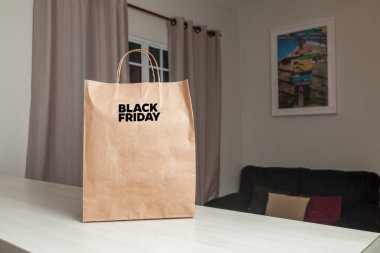 Karton poşet, arka planda özel yazı ve mutfak olan masa kahverengi kağıt ambalajına Kara Cuma yazılıydı. Kara Cuma konsepti. Ürün konsepti. Paketleme konsepti. Boşluğu kopyala