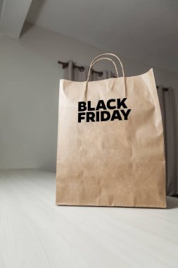 Karton poşet, arka planda özel yazı ve mutfak olan masa kahverengi kağıt ambalajına Kara Cuma yazılıydı. Kara Cuma konsepti. Ürün konsepti. Paketleme konsepti. Boşluğu kopyala