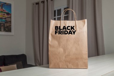 Karton poşet, arka planda özel yazı ve mutfak olan masa kahverengi kağıt ambalajına Kara Cuma yazılıydı. Kara Cuma konsepti. Ürün konsepti. Paketleme konsepti. Boşluğu kopyala