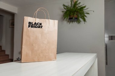 Karton poşet, arka planda özel yazı ve mutfak olan masa kahverengi kağıt ambalajına Kara Cuma yazılıydı. Kara Cuma konsepti. Ürün konsepti. Paketleme konsepti. Boşluğu kopyala