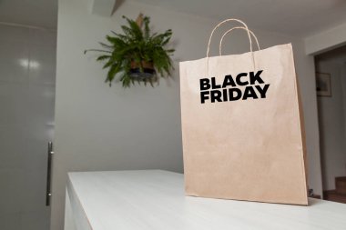 Karton poşet, arka planda özel yazı ve mutfak olan masa kahverengi kağıt ambalajına Kara Cuma yazılıydı. Kara Cuma konsepti. Ürün konsepti. Paketleme konsepti. Boşluğu kopyala