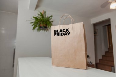 Karton poşet, arka planda özel yazı ve mutfak olan masa kahverengi kağıt ambalajına Kara Cuma yazılıydı. Kara Cuma konsepti. Ürün konsepti. Paketleme konsepti. Boşluğu kopyala