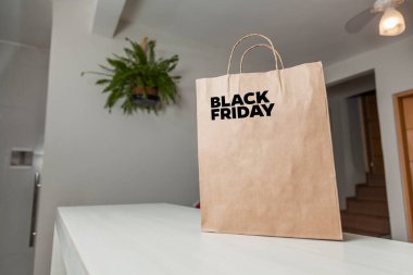 Karton poşet, arka planda özel yazı ve mutfak olan masa kahverengi kağıt ambalajına Kara Cuma yazılıydı. Kara Cuma konsepti. Ürün konsepti. Paketleme konsepti. Boşluğu kopyala