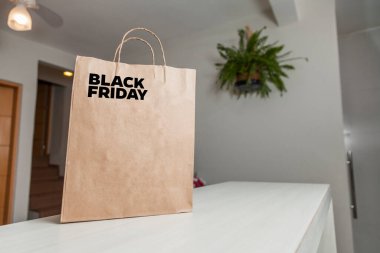 Karton poşet, arka planda özel yazı ve mutfak olan masa kahverengi kağıt ambalajına Kara Cuma yazılıydı. Kara Cuma konsepti. Ürün konsepti. Paketleme konsepti. Boşluğu kopyala