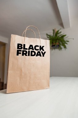 Karton poşet, arka planda özel yazı ve mutfak olan masa kahverengi kağıt ambalajına Kara Cuma yazılıydı. Kara Cuma konsepti. Ürün konsepti. Paketleme konsepti. Boşluğu kopyala