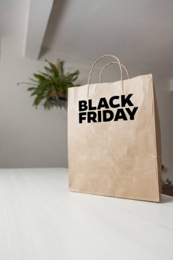 Karton poşet, arka planda özel yazı ve mutfak olan masa kahverengi kağıt ambalajına Kara Cuma yazılıydı. Kara Cuma konsepti. Ürün konsepti. Paketleme konsepti. Boşluğu kopyala