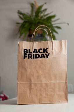 Karton poşet, arka planda özel yazı ve mutfak olan masa kahverengi kağıt ambalajına Kara Cuma yazılıydı. Kara Cuma konsepti. Ürün konsepti. Paketleme konsepti. Boşluğu kopyala