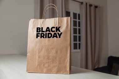 Karton poşet, arka planda özel yazı ve mutfak olan masa kahverengi kağıt ambalajına Kara Cuma yazılıydı. Kara Cuma konsepti. Ürün konsepti. Paketleme konsepti. Boşluğu kopyala