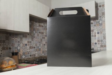 Ahşap masaya hediye paketi, reklam ve fotokopi alanı ile birlikte. Düz siyah karton kutu. Teslimat konsepti. Nakliye kavramı