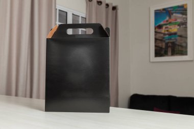 Ahşap masaya hediye paketi, reklam ve fotokopi alanı ile birlikte. Düz siyah karton kutu. Teslimat konsepti. Nakliye kavramı