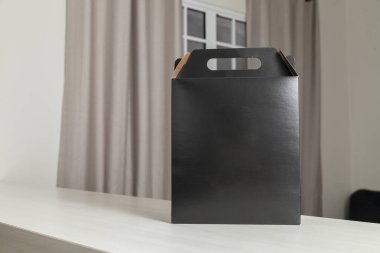 Ahşap masaya hediye paketi, reklam ve fotokopi alanı ile birlikte. Düz siyah karton kutu. Teslimat konsepti. Nakliye kavramı