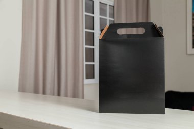 Ahşap masaya hediye paketi, reklam ve fotokopi alanı ile birlikte. Düz siyah karton kutu. Teslimat konsepti. Nakliye kavramı