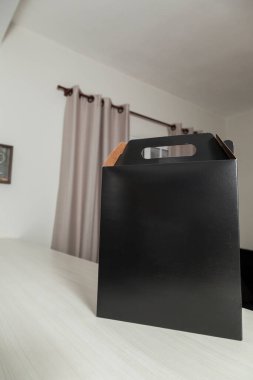 Ahşap masaya hediye paketi, reklam ve fotokopi alanı ile birlikte. Düz siyah karton kutu. Teslimat konsepti. Nakliye kavramı