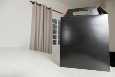 Ahşap masaya hediye paketi, reklam ve fotokopi alanı ile birlikte. Düz siyah karton kutu. Teslimat konsepti. Nakliye kavramı