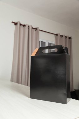 Ahşap masaya hediye paketi, reklam ve fotokopi alanı ile birlikte. Düz siyah karton kutu. Teslimat konsepti. Nakliye kavramı