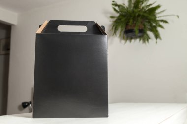 Ahşap masaya hediye paketi, reklam ve fotokopi alanı ile birlikte. Düz siyah karton kutu. Teslimat konsepti. Nakliye kavramı