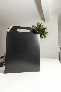 Ahşap masaya hediye paketi, reklam ve fotokopi alanı ile birlikte. Düz siyah karton kutu. Teslimat konsepti. Nakliye kavramı