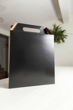 Ahşap masaya hediye paketi, reklam ve fotokopi alanı ile birlikte. Düz siyah karton kutu. Teslimat konsepti. Nakliye kavramı