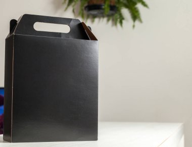 Ahşap masaya hediye paketi, reklam ve fotokopi alanı ile birlikte. Düz siyah karton kutu. Teslimat konsepti. Nakliye kavramı