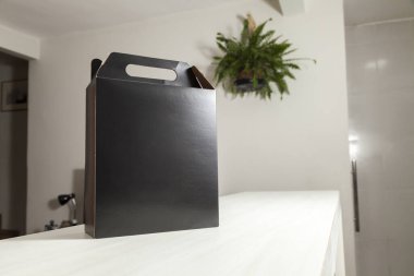 Ahşap masaya hediye paketi, reklam ve fotokopi alanı ile birlikte. Düz siyah karton kutu. Teslimat konsepti. Nakliye kavramı