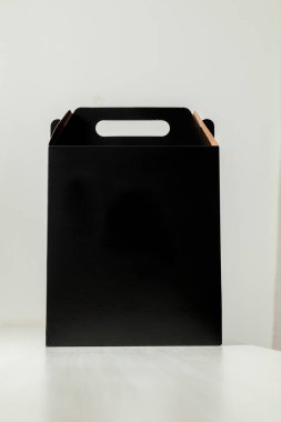 Ahşap masaya hediye paketi, reklam ve fotokopi alanı ile birlikte. Düz siyah karton kutu. Teslimat konsepti. Nakliye kavramı