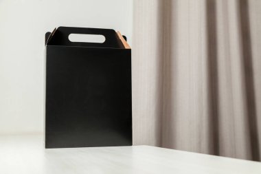 Ahşap masaya hediye paketi, reklam ve fotokopi alanı ile birlikte. Düz siyah karton kutu. Teslimat konsepti. Nakliye kavramı