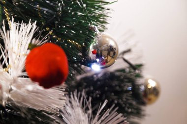 Christmas ornaments. With copy space and neutral background. Green Christmas tree with red and gold and silver ornaments. Year-end party concept. New year concept. Christmas lights.	