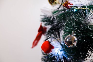 Christmas ornaments. With copy space and neutral background. Green Christmas tree with red and gold and silver ornaments. Year-end party concept. New year concept. Christmas lights.	