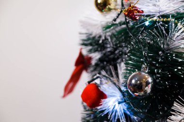Christmas ornaments. With copy space and neutral background. Green Christmas tree with red and gold and silver ornaments. Year-end party concept. New year concept. Christmas lights.	