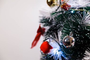 Christmas ornaments. With copy space and neutral background. Green Christmas tree with red and gold and silver ornaments. Year-end party concept. New year concept. Christmas lights.	
