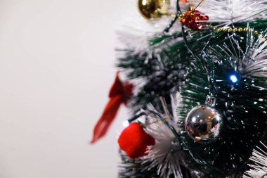 Christmas ornaments. With copy space and neutral background. Green Christmas tree with red and gold and silver ornaments. Year-end party concept. New year concept. Christmas lights.	