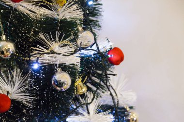 Christmas ornaments. With copy space and neutral background. Green Christmas tree with red and gold and silver ornaments. Year-end party concept. New year concept. Christmas lights.	