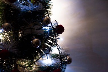 Christmas ornaments. With copy space and neutral background. Green Christmas tree with red and gold and silver ornaments. Year-end party concept. New year concept. Christmas lights.	