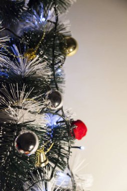 Christmas ornaments. With copy space and neutral background. Green Christmas tree with red and gold and silver ornaments. Year-end party concept. New year concept. Christmas lights.	