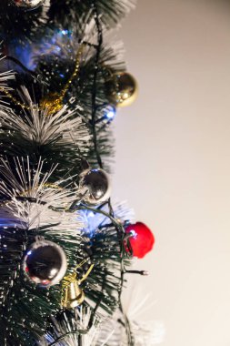 Christmas ornaments. With copy space and neutral background. Green Christmas tree with red and gold and silver ornaments. Year-end party concept. New year concept. Christmas lights.	