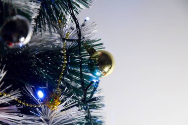 Christmas ornaments. With copy space and neutral background. Green Christmas tree with red and gold and silver ornaments. Year-end party concept. New year concept. Christmas lights.	