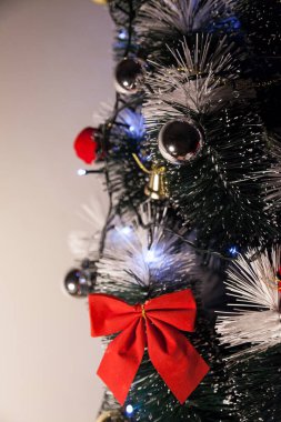 Noel ağacını kırmızı halkayla süslemek güzel ve uyumlu bir ortam yaratıyor. Hristiyan kültürünün mutluluk getiren şenliği ve geleneği. Noel konsepti. Uzayı kopyala Selam ver.