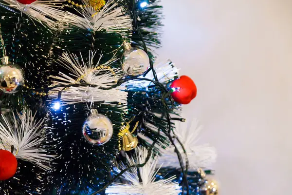 Christmas ornaments. With copy space and neutral background. Green Christmas tree with red and gold and silver ornaments. Year-end party concept. New year concept. Christmas lights.	