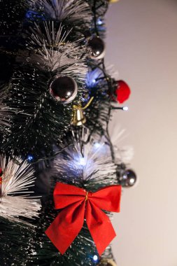 Noel ağacını kırmızı halkayla süslemek güzel ve uyumlu bir ortam yaratıyor. Hristiyan kültürünün mutluluk getiren şenliği ve geleneği. Noel konsepti. Uzayı kopyala Selam ver.