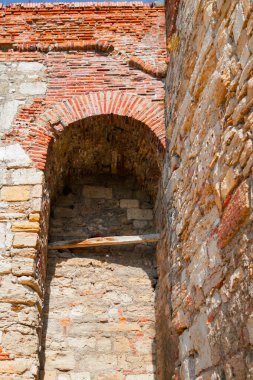 Antik bir taş yapıya yakından bakınca karmaşık tuğla ve yıpranmış taşlar görülüyor. Yumuşak ışık yüzyıllardır var olan dokuları ve işçiliği vurguluyor..