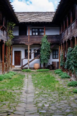 Büyüleyici bir avluda geleneksel ahşap mimariyle çevrili taş bir patika bulunur. Bereketli yeşillik huzur dolu bir gökyüzünün altındaki huzurlu ortama canlılık katıyor..