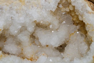 Karmaşık kristal kümeleri, ışığı yansıtan bir kaya boşluğunun içinde görülebilir. Bu oluşum zamanla doğal jeolojik süreçleri ve mineral yapıların güzelliğini vurgular..
