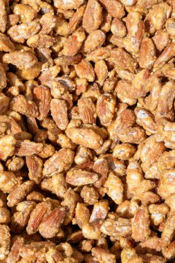 Karamel kaplı çıtır çıtır badem kümelerinin yakın plan görüntüsü, altın-kahverengi renklerini ve dokularını gözler önüne seriyor..