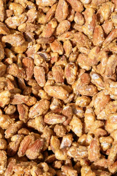 Karamel kaplı çıtır çıtır badem kümelerinin yakın plan görüntüsü, altın-kahverengi renklerini ve dokularını gözler önüne seriyor..