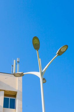 Bir binanın üzerine monte edilmiş üç zarif sokak lambası, şehir ortamında modern mimarinin yanında yenilikçi kentsel ışıklandırma tasarımı sergiliyor..