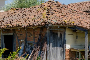 Antika bir çiftlik evi, sera ile çevrili terasotta fayanslarından yapılmış belirgin yıpranmış bir çatıya sahiptir..